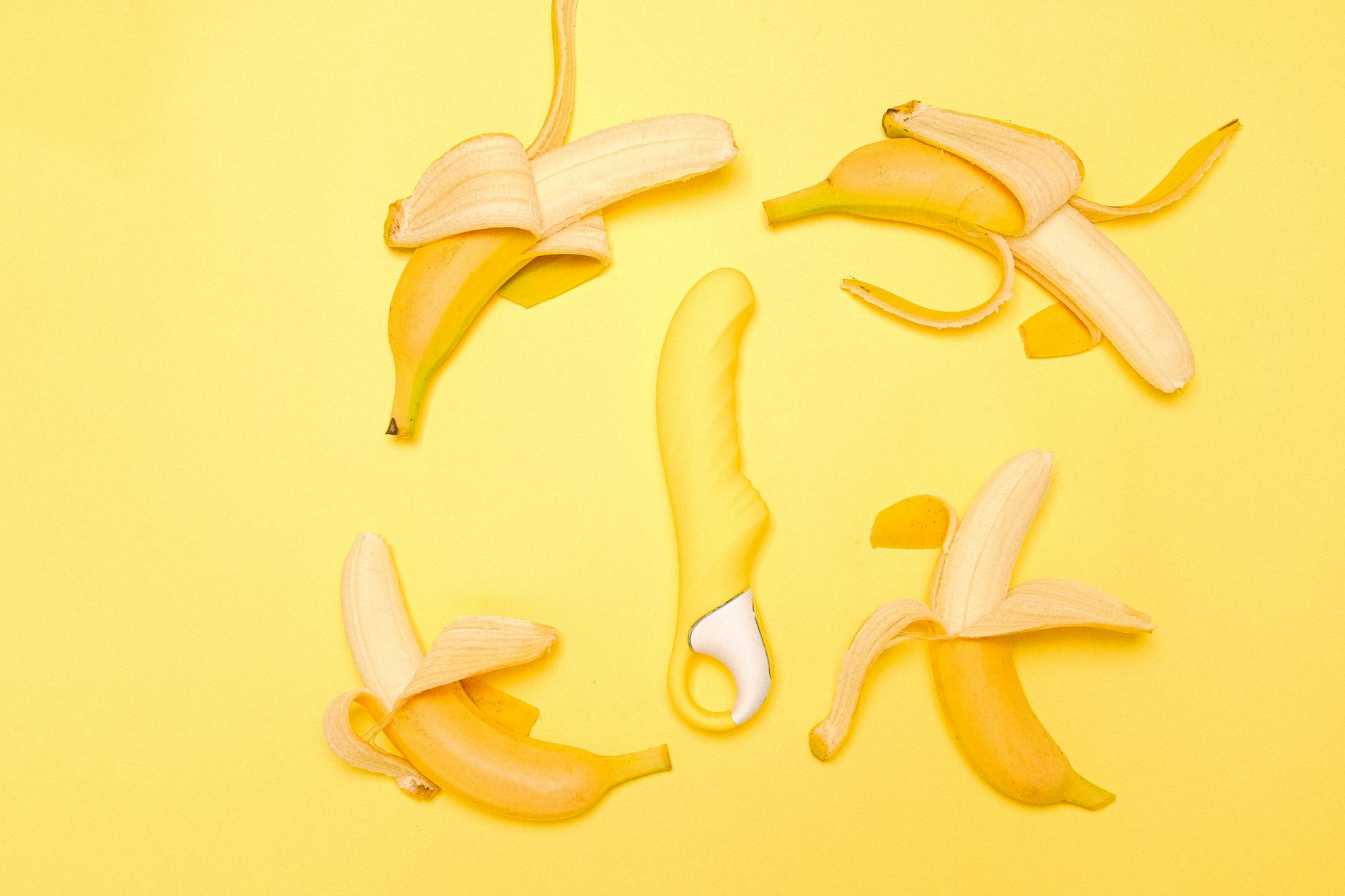 A yellow lemon vibrator surrounded by fresh lemons on a bright yellow background, symbolizing natural pleasure and sensual exploration